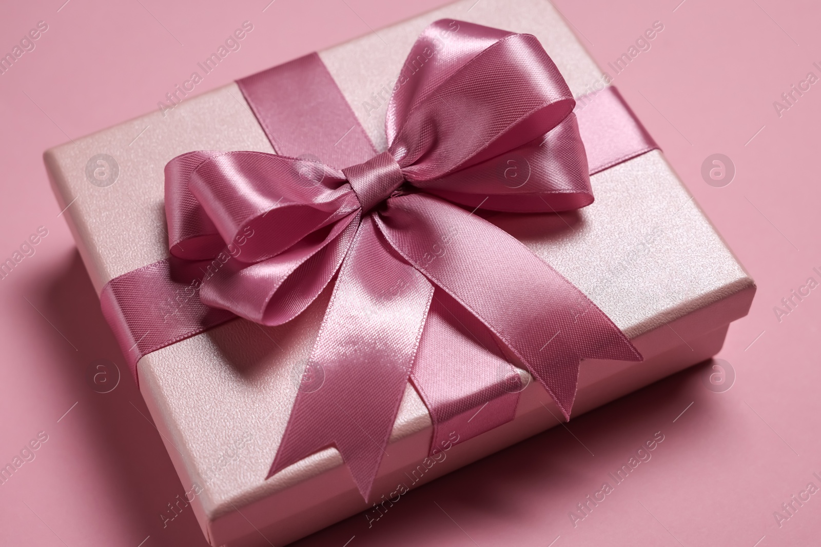 Photo of Gift box with bow on dusty pink background, closeup