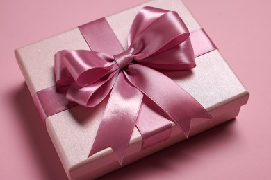 Gift box with bow on dusty pink background, closeup