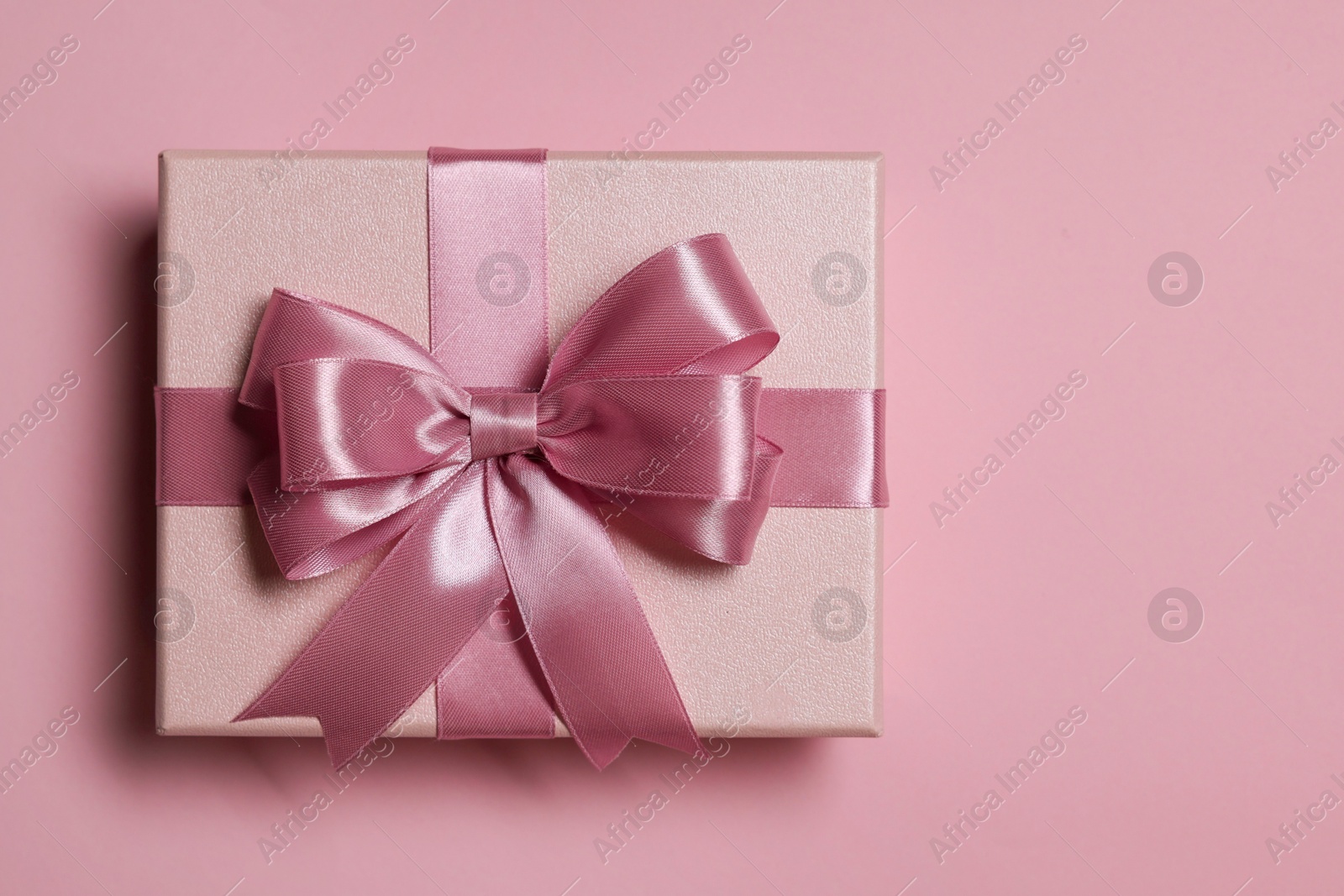 Photo of Gift box with bow on dusty pink background, top view