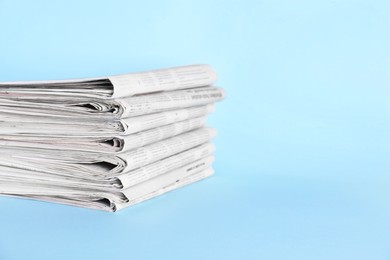 Stack of newspapers on light blue background, space for text