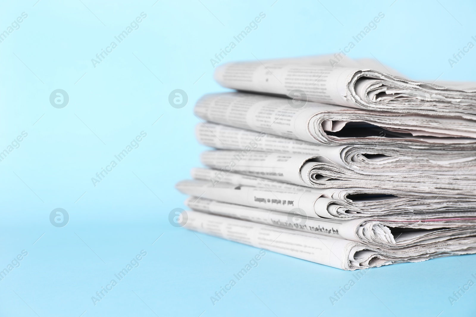 Photo of Stack of newspapers on light blue background, space for text