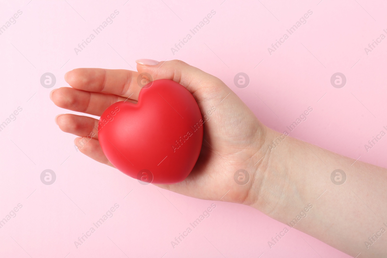 Photo of Woman holding red heart on pink background, top view