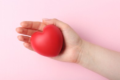 Photo of Woman holding red heart on pink background, top view