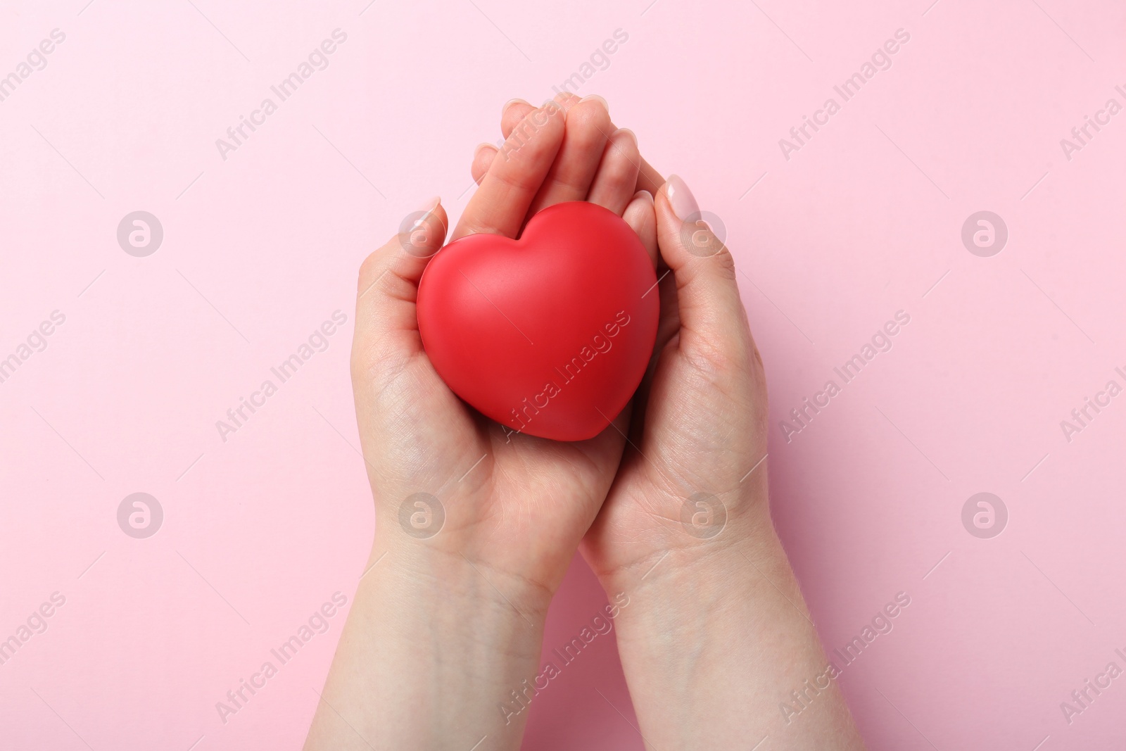 Photo of Woman holding red heart on pink background, top view