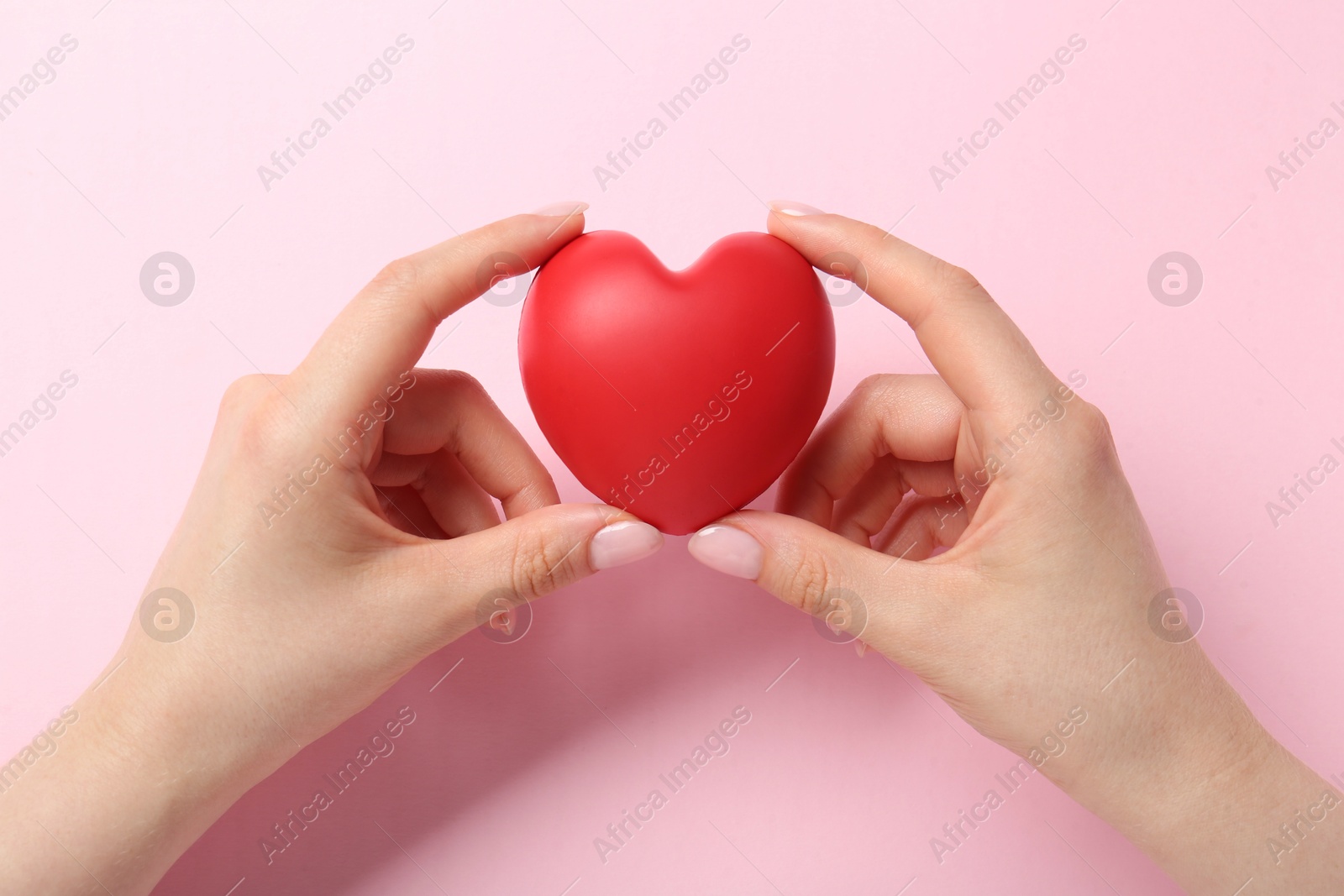 Photo of Woman holding red heart on pink background, top view