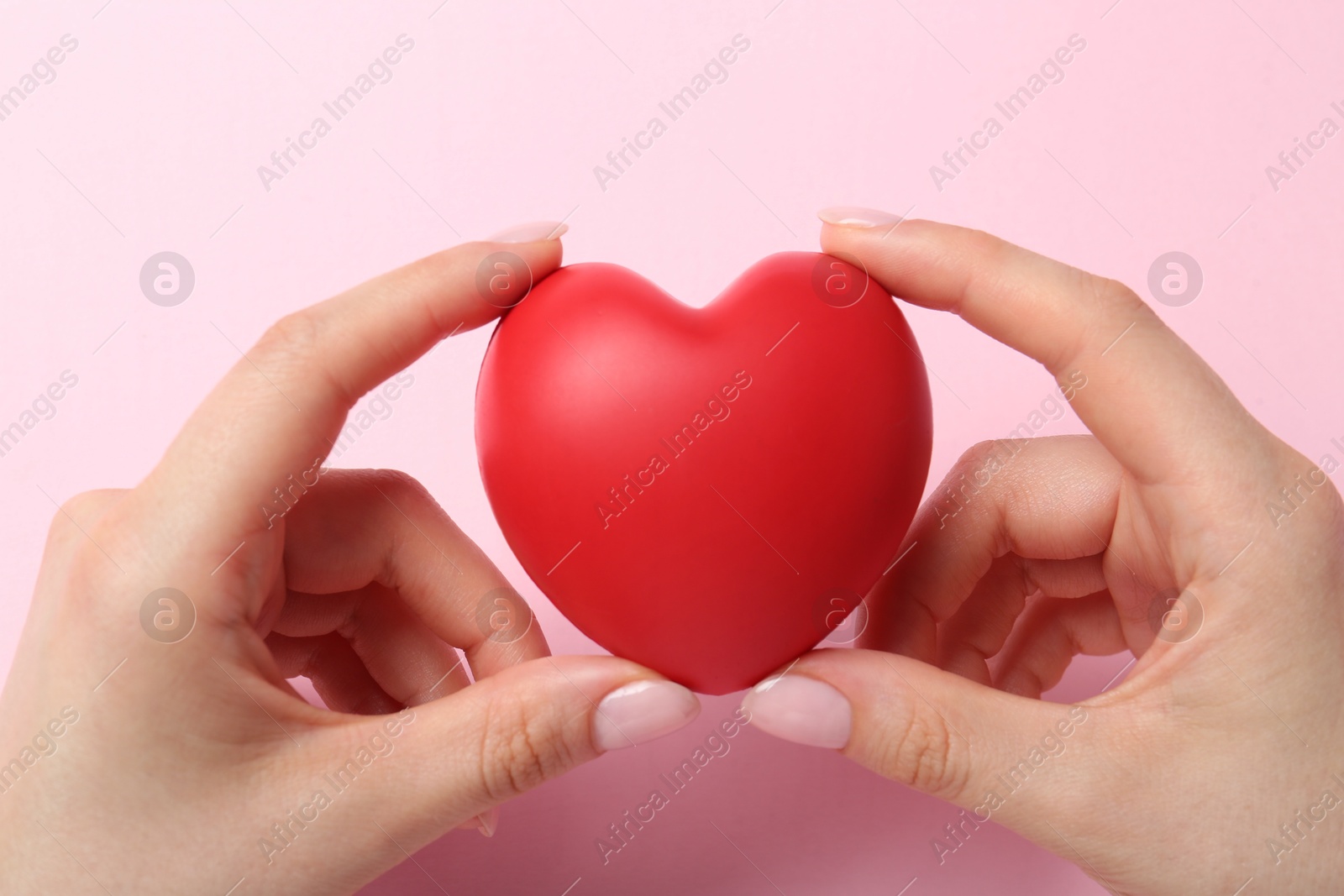 Photo of Woman holding red heart on pink background, top view