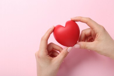 Photo of Woman holding red heart on pink background, top view. Space for text