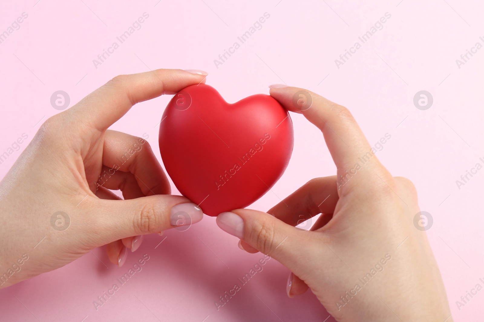 Photo of Woman holding red heart on pink background, top view