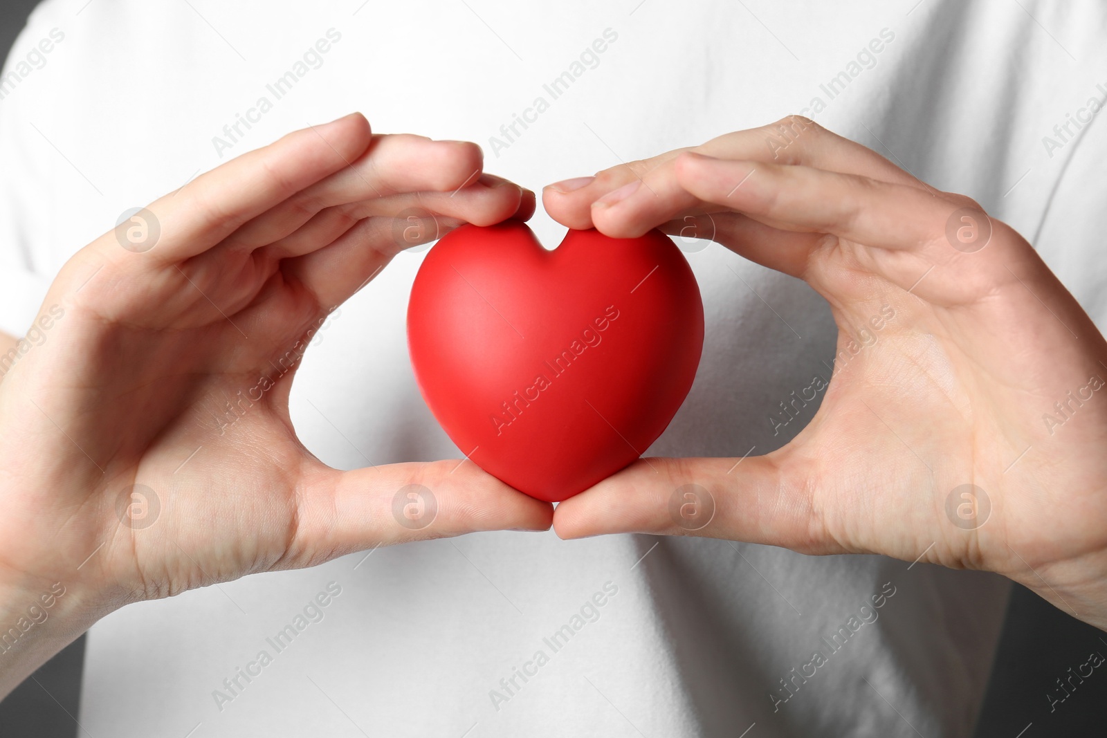 Photo of Woman holding red heart on grey background, closeup