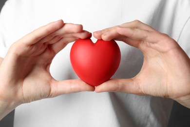 Photo of Woman holding red heart on grey background, closeup