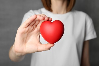 Photo of Woman holding red heart on grey background, closeup