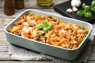 Photo of Delicious al forno pasta in baking dish on wooden table, closeup