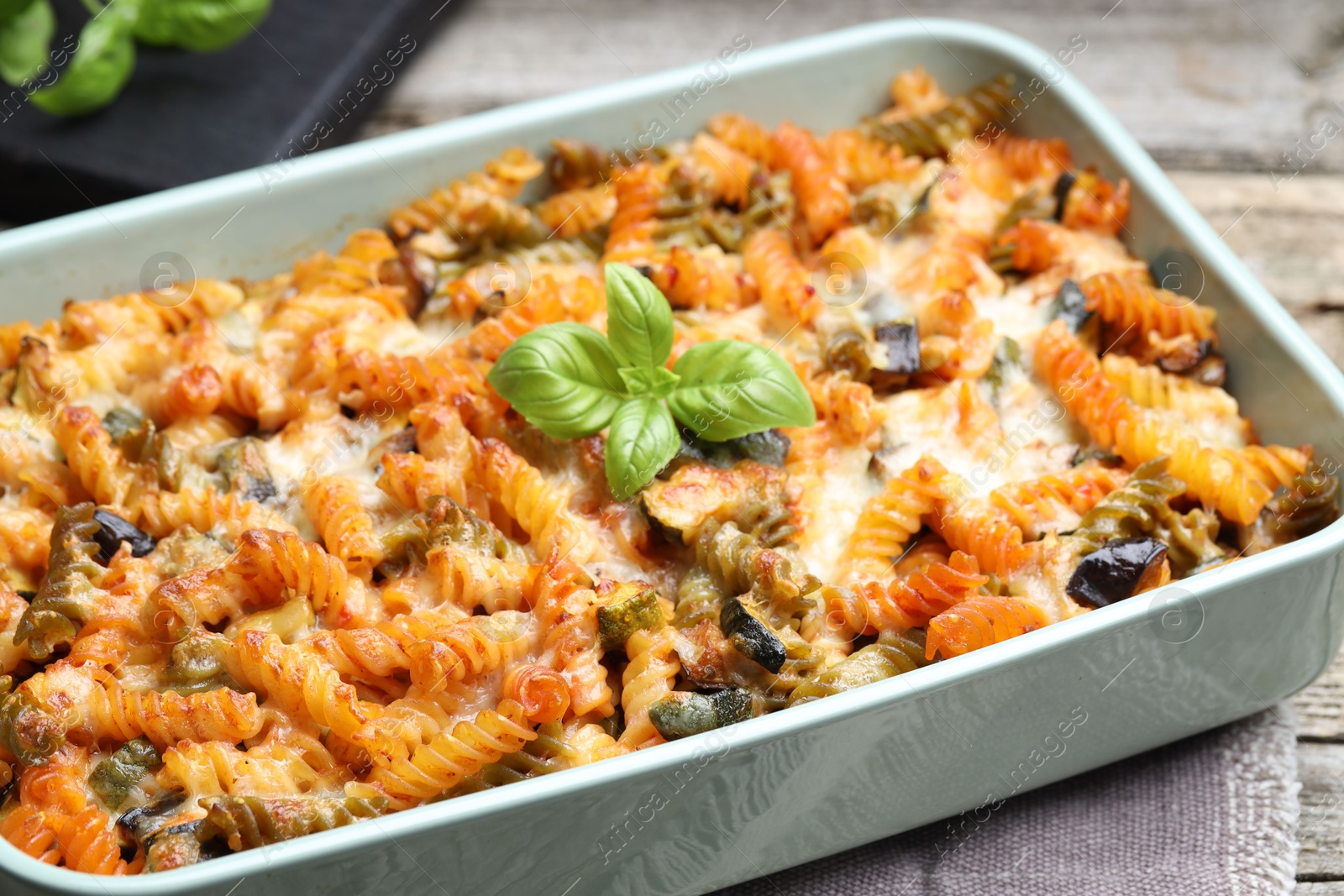 Photo of Delicious al forno pasta in baking dish on wooden table, closeup