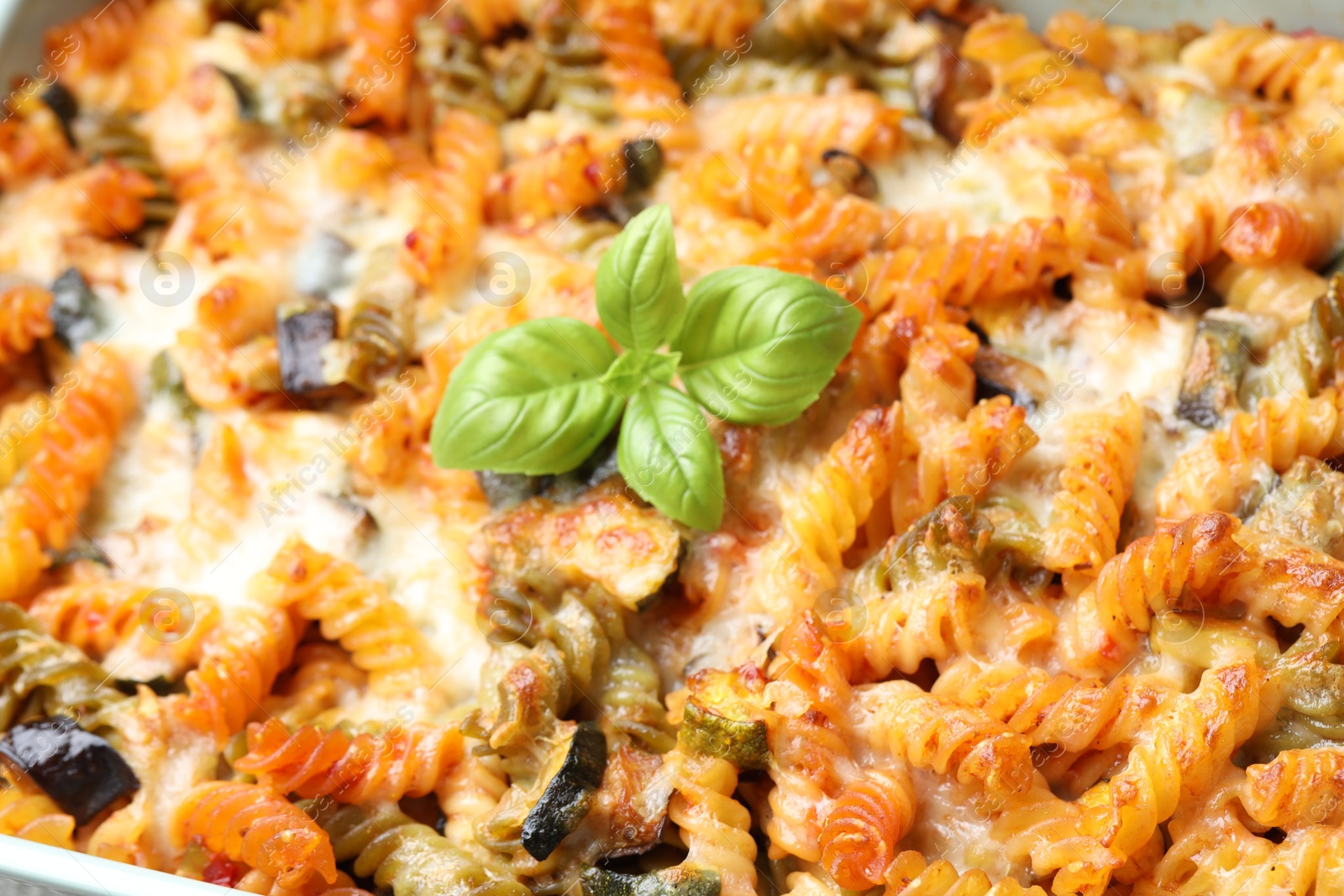 Photo of Delicious al forno pasta with basil, closeup