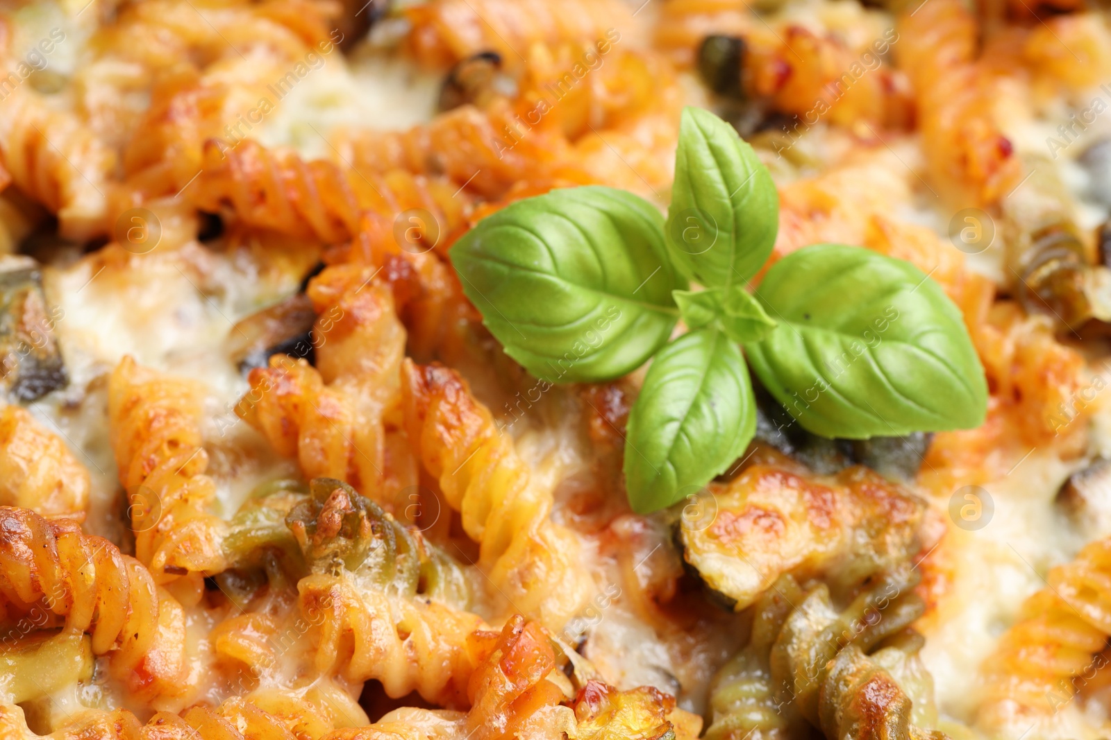 Photo of Delicious al forno pasta with basil, closeup