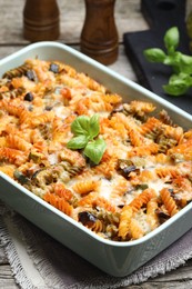 Photo of Delicious al forno pasta in baking dish on wooden table, closeup