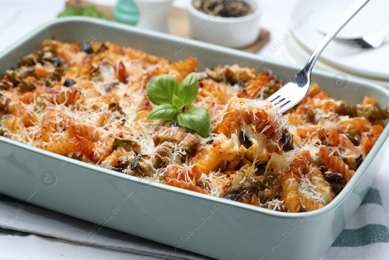 Photo of Eating delicious al forno pasta at white table, closeup