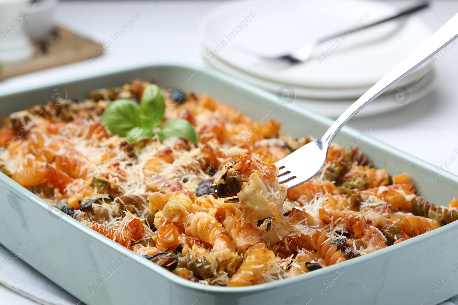 Photo of Eating delicious al forno pasta at white table, closeup