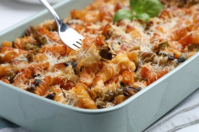 Photo of Eating delicious al forno pasta at white table, closeup