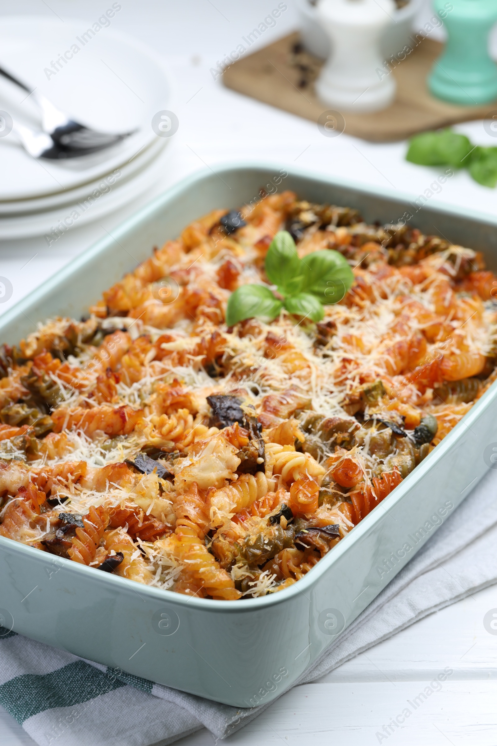 Photo of Delicious al forno pasta in baking dish on white wooden table, closeup