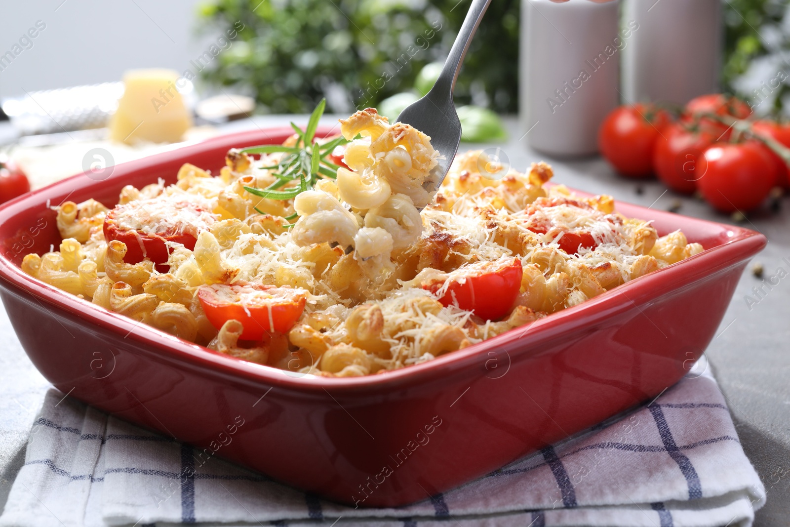 Photo of Eating delicious al forno pasta at grey table, closeup