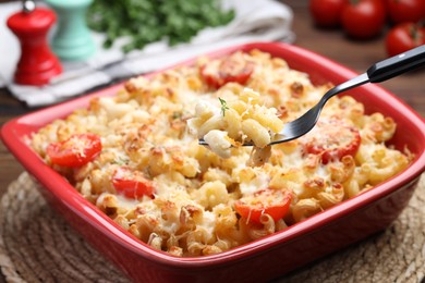 Photo of Eating delicious al forno pasta at wooden table, closeup