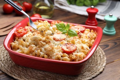 Photo of Eating delicious al forno pasta at wooden table, closeup