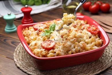 Photo of Eating delicious al forno pasta at wooden table, closeup