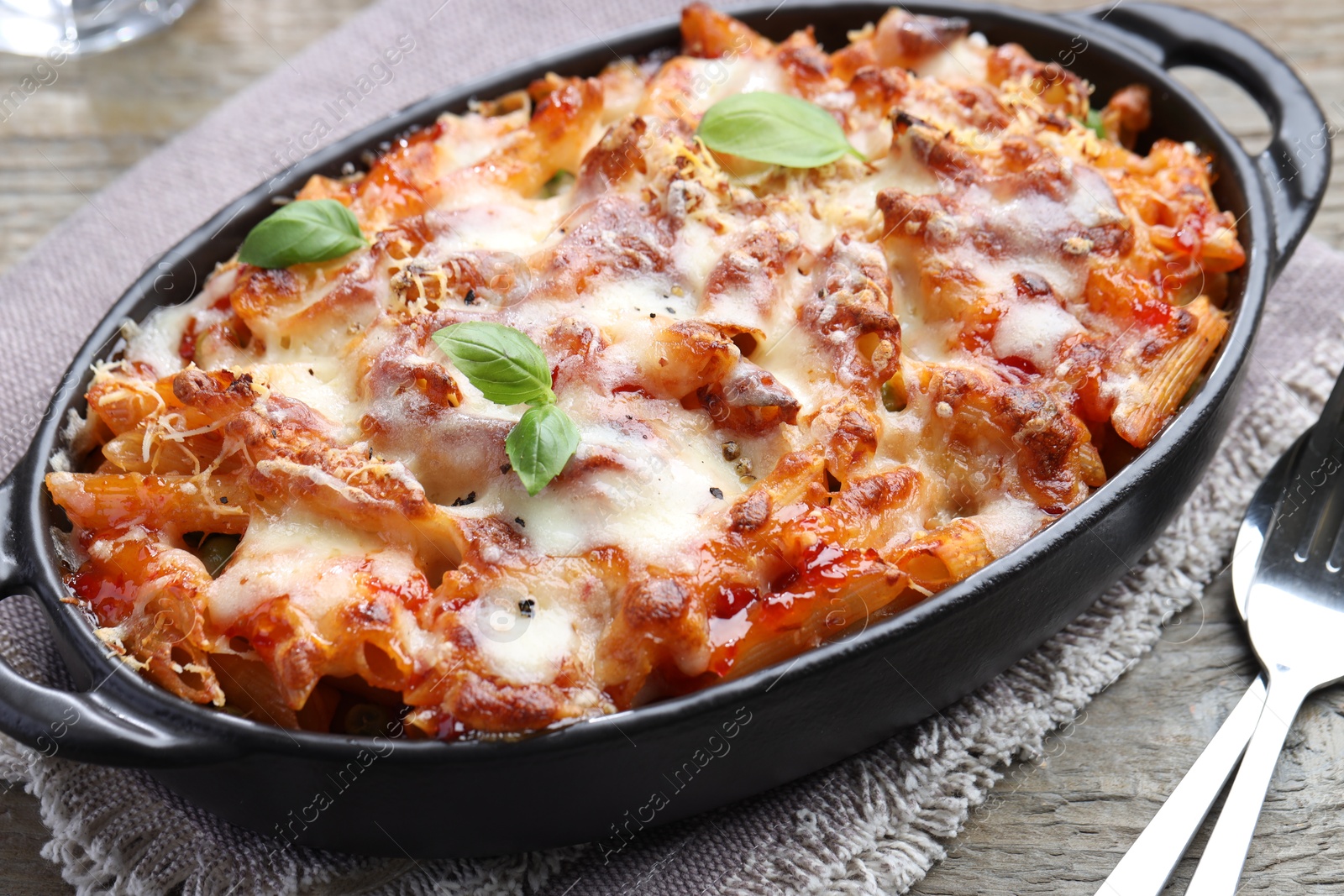 Photo of Delicious al forno pasta in baking dish on wooden table, closeup