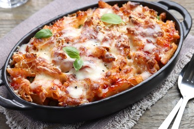 Photo of Delicious al forno pasta in baking dish on wooden table, closeup