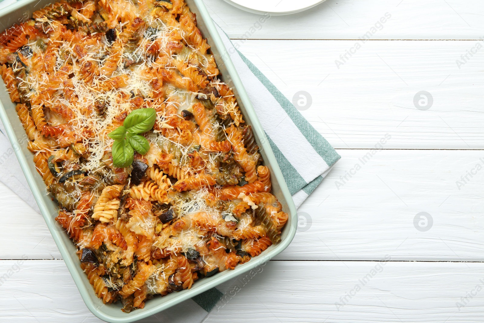 Photo of Delicious al forno pasta in baking dish on white wooden table, top view. Space for text