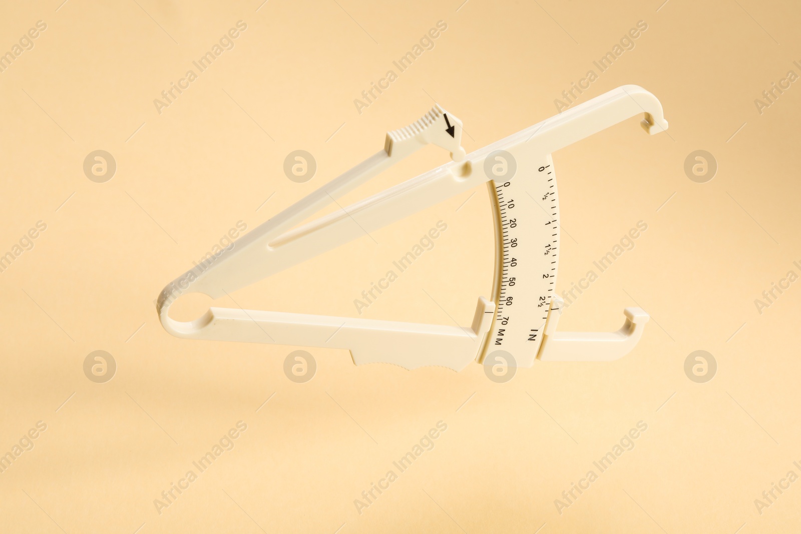 Photo of Plastic body fat caliper on beige background