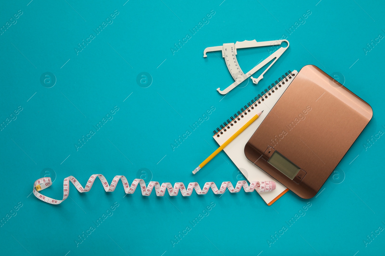 Photo of Body fat caliper, measuring tape, kitchen scale and notebook on light blue background, flat lay. Space for text