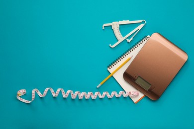 Photo of Body fat caliper, measuring tape, kitchen scale and notebook on light blue background, flat lay. Space for text