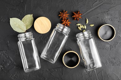 Photo of Different spices and glass jars on black table, flat lay