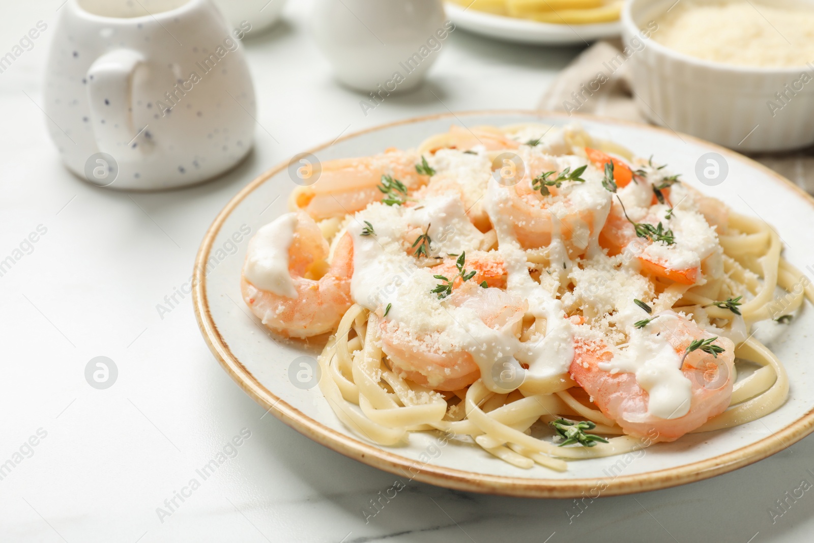 Photo of Tasty pasta with shrimps, creamy sauce and cheese on white marble table, closeup