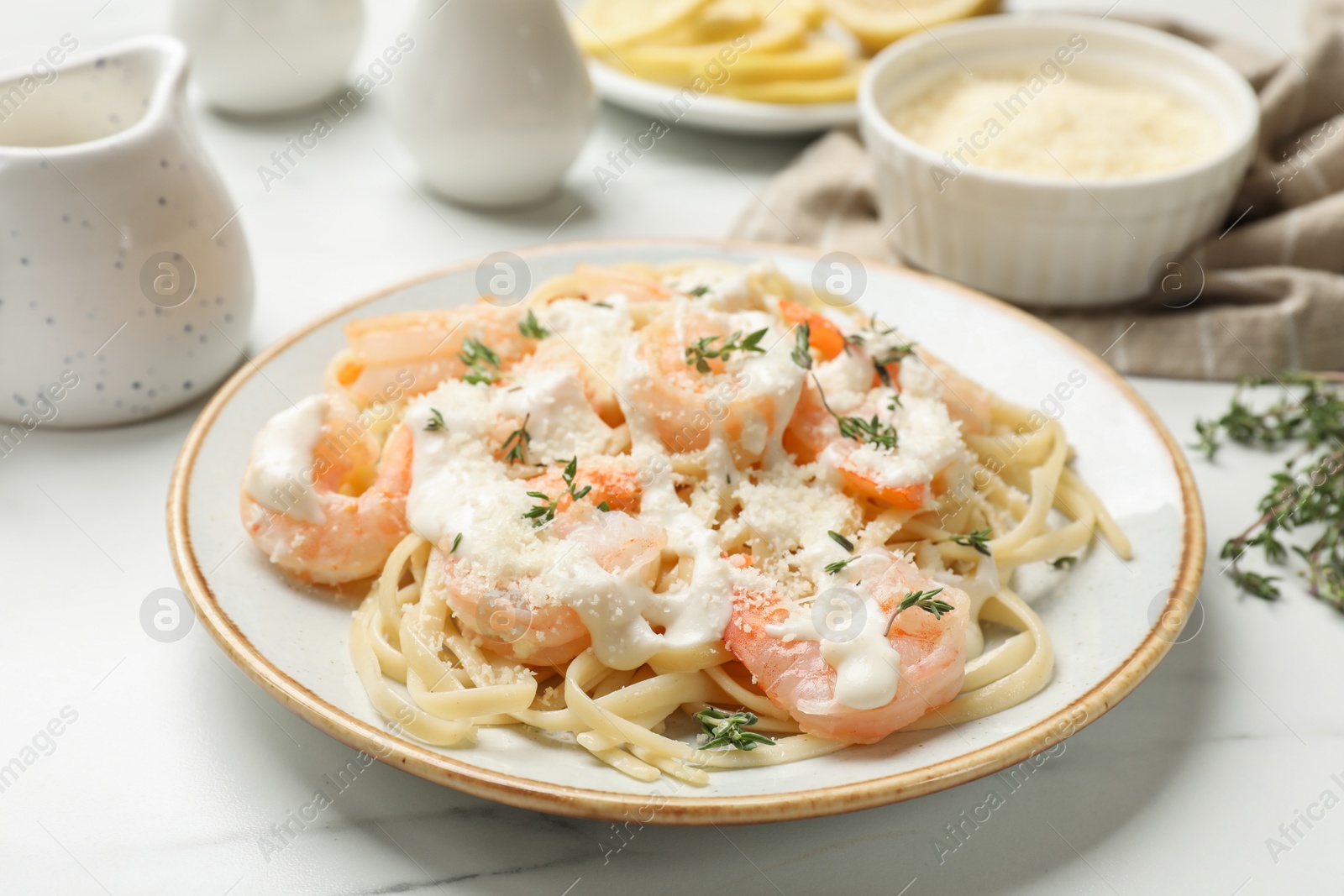 Photo of Tasty pasta with shrimps, creamy sauce and cheese on white marble table, closeup