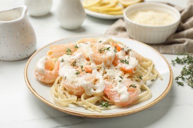 Photo of Tasty pasta with shrimps, creamy sauce and cheese on white marble table, closeup