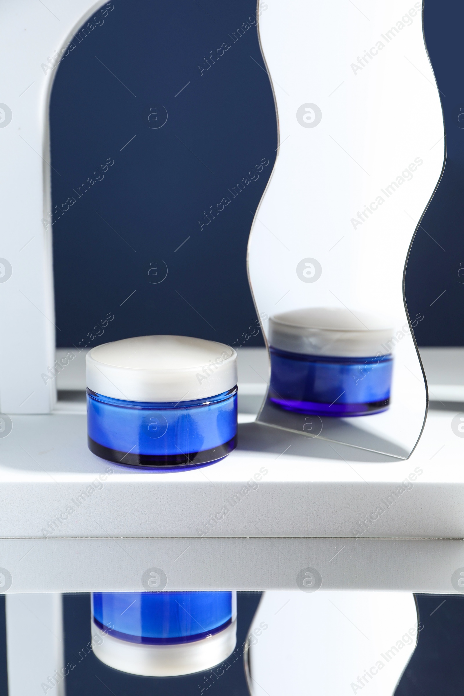 Photo of Stylish presentation of face cream against blue background