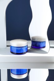 Photo of Stylish presentation of face cream against blue background