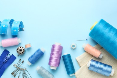 Photo of Flat lay composition with different sewing supplies on light blue background. Space for text