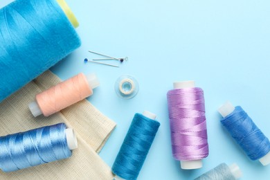 Flat lay composition with different sewing supplies on light blue background