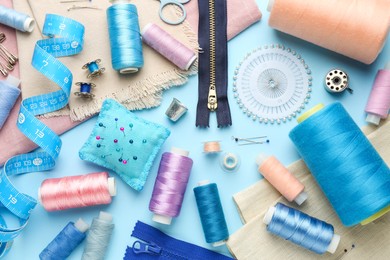 Flat lay composition with different sewing supplies on light blue background