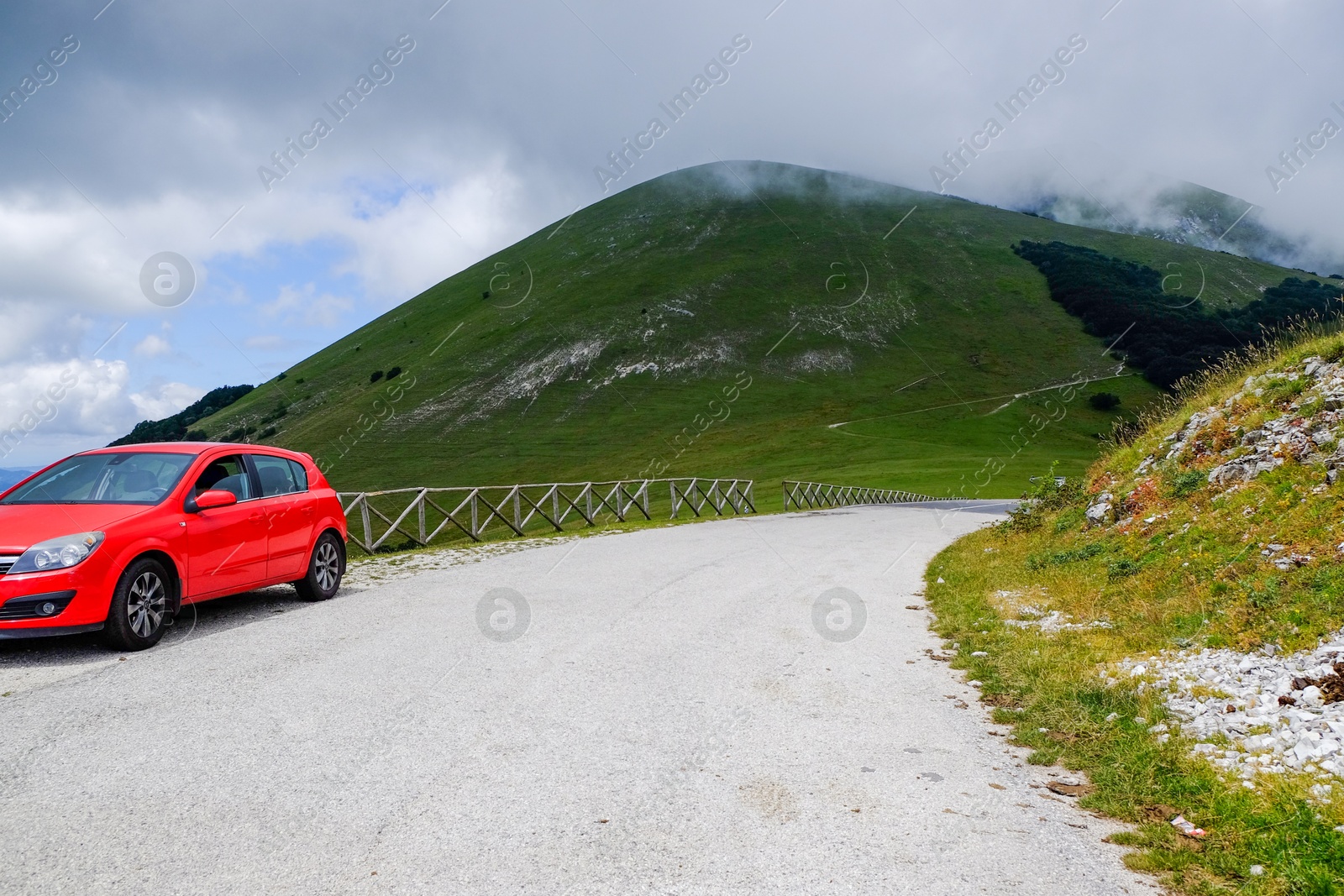 Photo of Picturesque view of green forest and red car in mountains