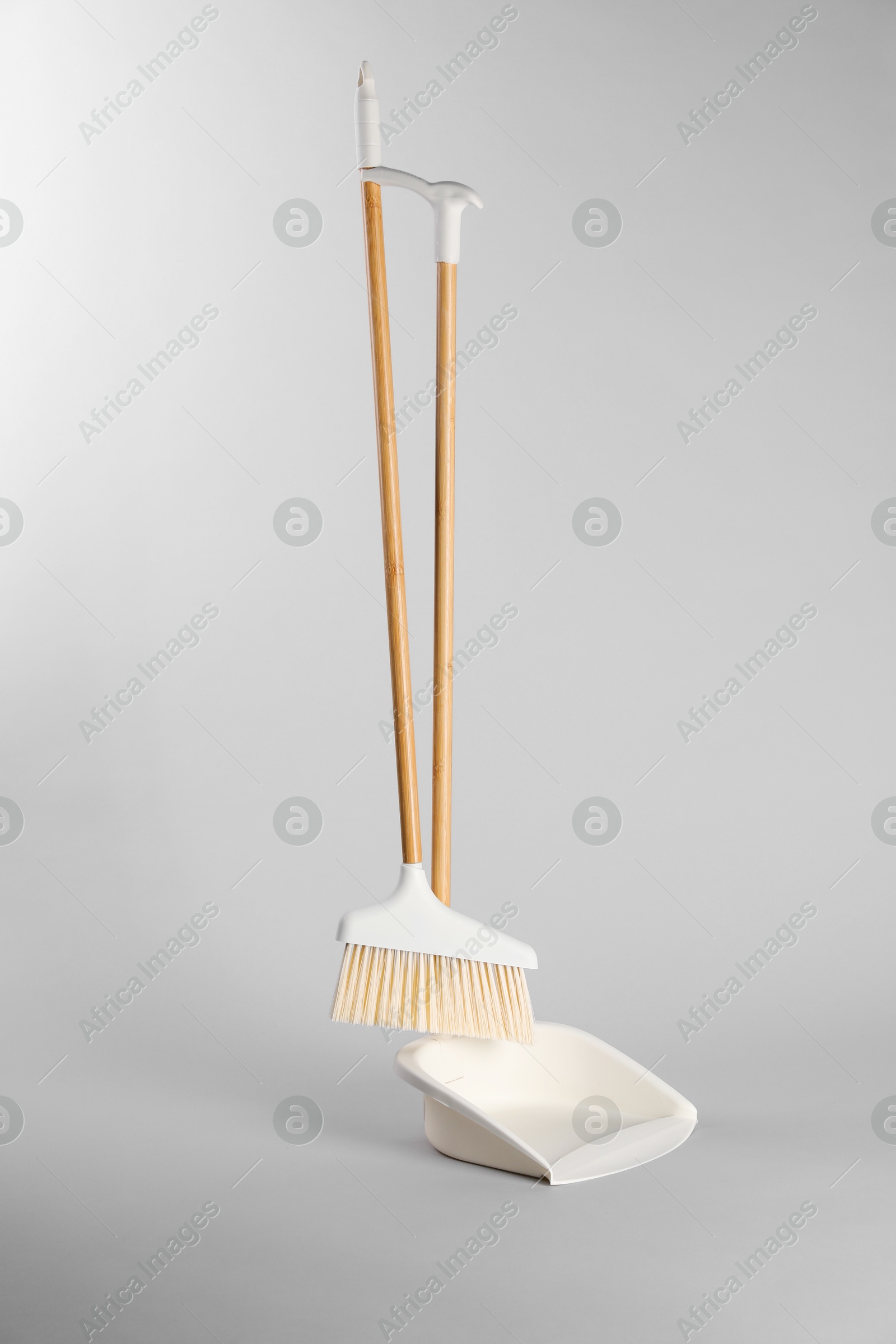 Photo of Cleaning broom and dustpan on grey background