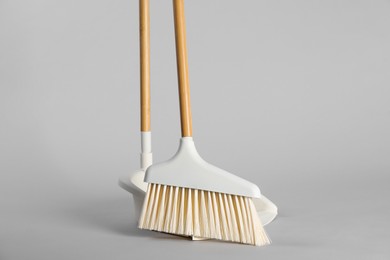 Photo of Cleaning broom and dustpan on grey background