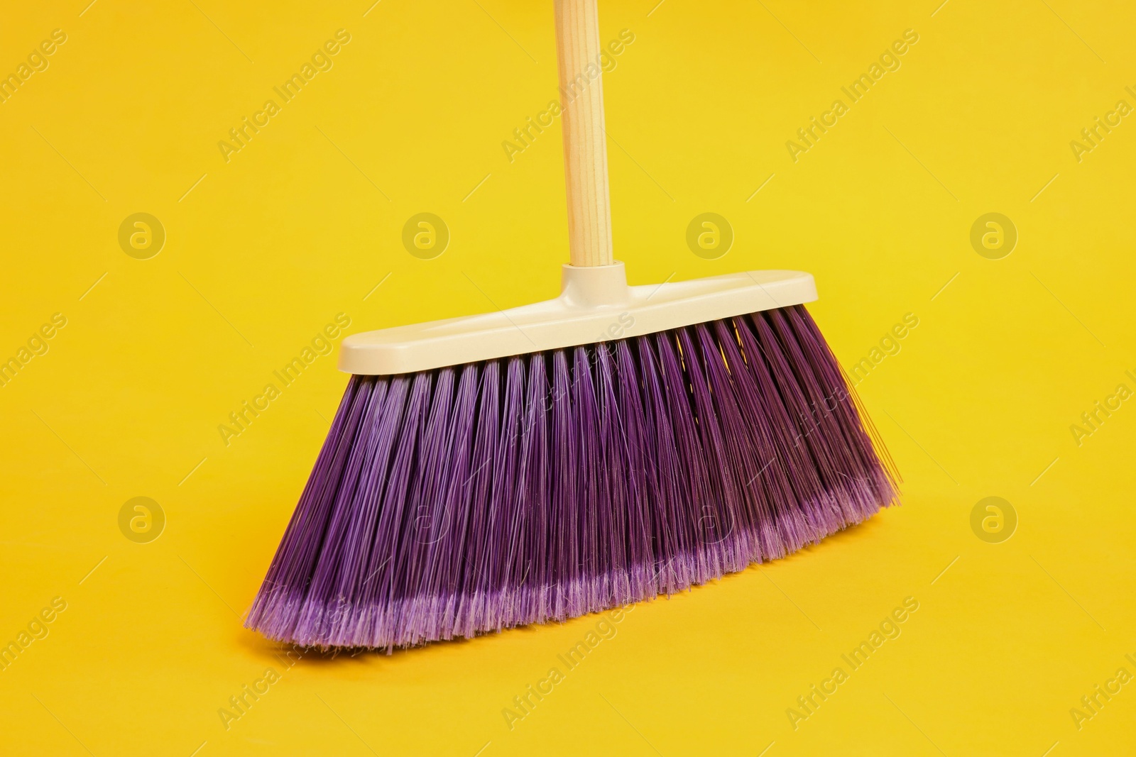 Photo of One bright cleaning broom on yellow background