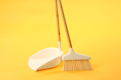 Photo of Cleaning broom and dustpan on yellow background