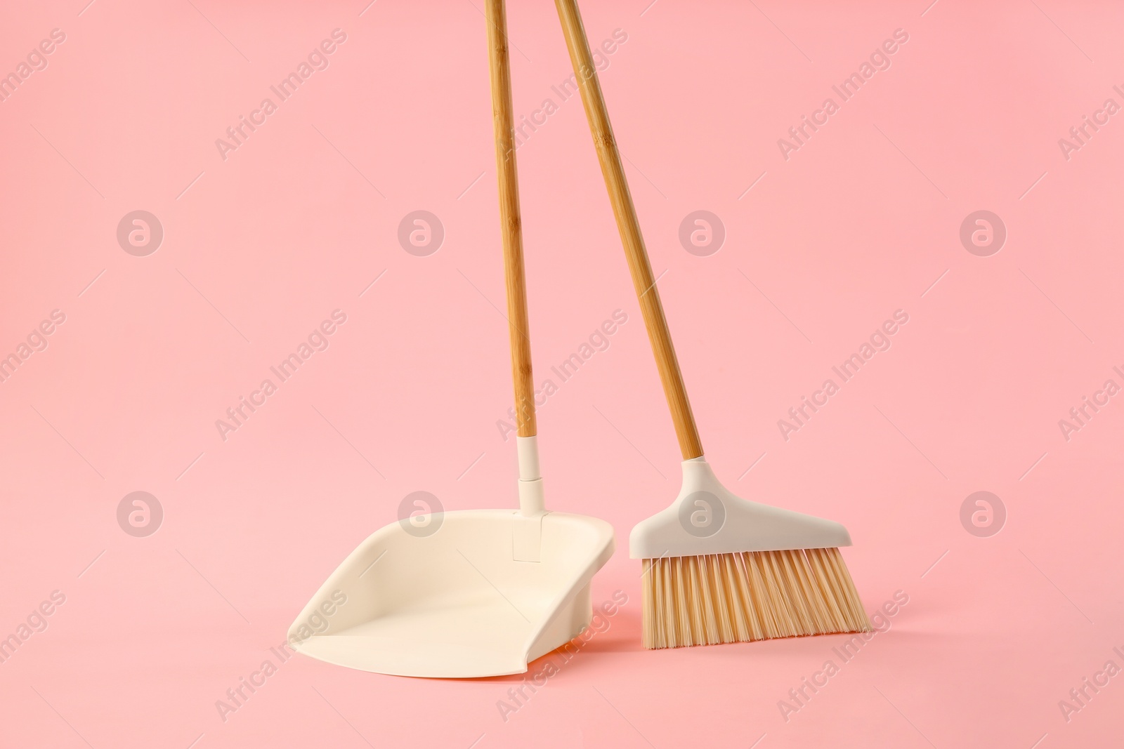 Photo of Cleaning broom and dustpan on pink background