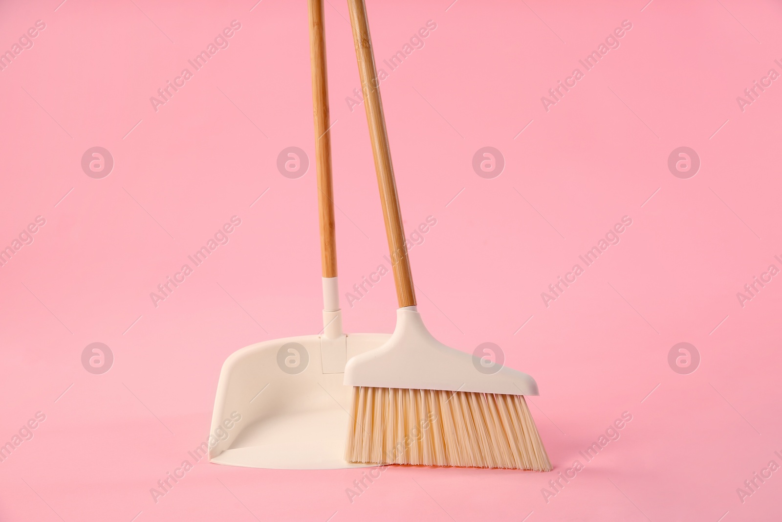 Photo of Cleaning broom and dustpan on pink background